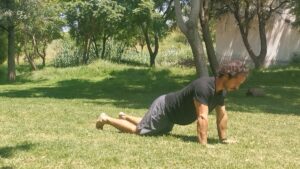 Hombre haciendo kneeling push ups de ejercicio en el césped.