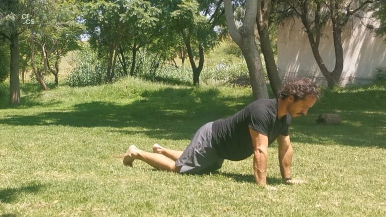 Hombre haciendo kneeling push ups de ejercicio en el césped.